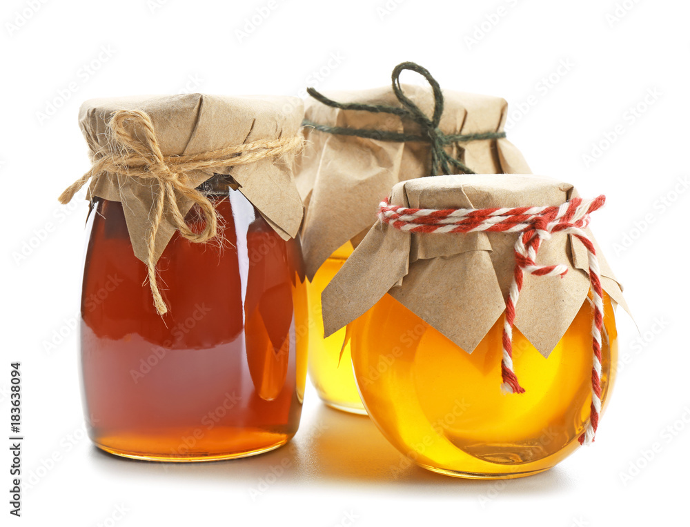 Jars with aromatic honey on white background