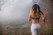 Woman jogging in the foggy autumn morning