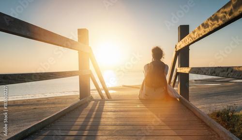 woman is sitting on a wooden path to the Baltic sea at sunset and relaxe the oce Slika na platnu