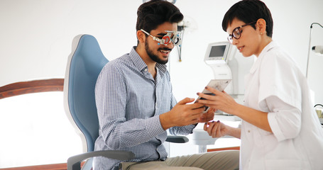 Sticker - Attentive optometrist examining female patient on slit lamp