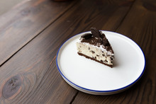 Creamy Cheesecake With Chocolate Chip Cookies. On A White Plate. On A Wooden Table.