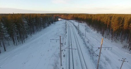 Wall Mural - Flying over wire above the center of a track. Electrified railway line with double-track railroad in wintry taiga forest. Northern Russia