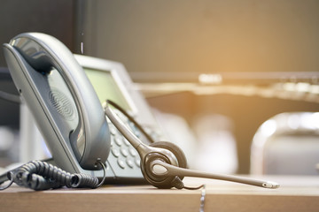 Wall Mural - close up soft focus on headphone of call center with telephone devices at office desk for customer service support concept