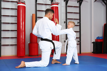 Wall Mural - Male karate instructor training little child in dojo