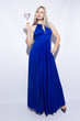 Portrait of a beautiful young blond woman with long hair in blue maxi dress. Girl holding a heart shaped candy.