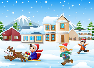Wall Mural - Cartoon boy riding sled on the snowing village with running kids