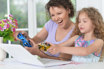 mother and daughter playing game on laptop