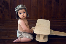 Baby Sits On The Floor Next To The Wooden Plane In The Studio