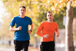 Handsome young men wearing sportswear and running at quay during autumn