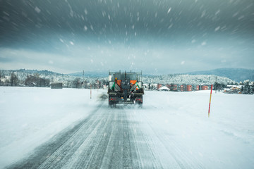 Winter service truck or gritter spreading salt on the road surface to prevent icing in stormy snow winter day.