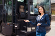 © VadimGuzhva - Woman stewardess posing against the backdrop of a black bus on which she works.