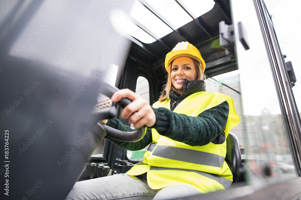Woman forklift truck driver in an industrial area. - obrazy, fototapety, plakaty 