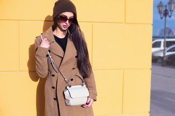 Wall Mural - Cheerful young woman in sunglasses against blue background. Beautiful female model with long hair.Outdoor photo of european girl with brown hair.Yellow wall background. 