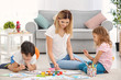 © Africa Studio - Mother with children painting while sitting on floor indoors