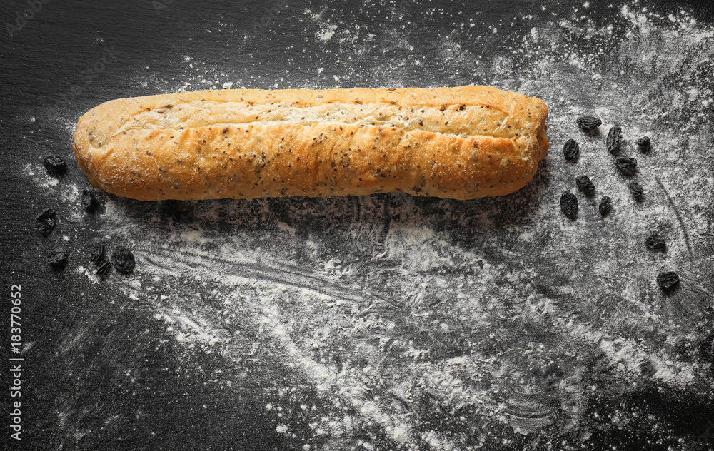 Yummy fresh bread and raisins on dark background