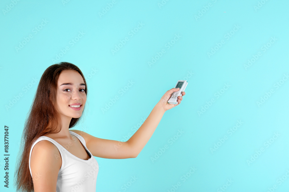 Woman with air conditioner remote control on color background
