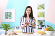© Africa Studio - Young woman holding strawberry for oatmeal porridge on table in kitchen