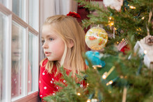 Beautiful Young School Age Girl Looking Out Window Waiting For Santa On Christmas Eve