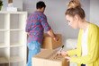 © Connect Images - Young couple moving home, young woman labelling cardboard box