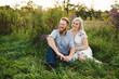 © Connect Images - Couple sitting in tall grass looking away smiling