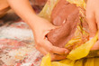 Close up of a woman hand manipulating a clay mass on wooden table in workshop, in a blurred background