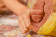 Close up of a woman hand manipulating a clay mass on wooden table in workshop, in a blurred background