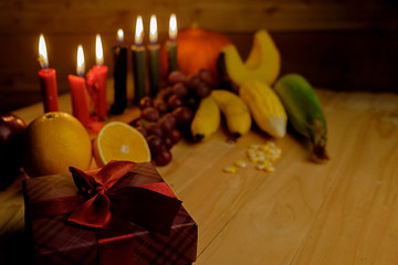 Kwanzaa holiday concept with decorate seven candles red, black and green, gift box, pumpkin,corn and fruit on wooden desk and background.