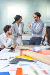 Young team of creative people discussing paperwork in the office.