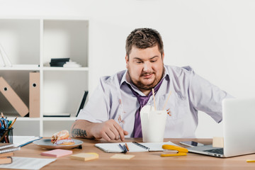 Wall Mural - overweight businessman eating noodles at workplace in office