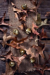 Wall Mural - Sequin balls and dry leaves on wooden plank