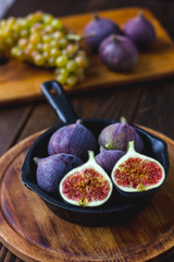 Wall Mural - Fresh and ripe figs inside frying pan over wooden table.