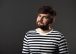 © nastia1983 - Bearded smiling emotional man in casual striped t-shirt on grey background with empty copy space. Closeup portrait.
