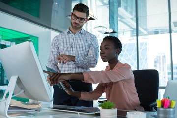 Wall Mural - Executives discussing over personal computer at desk