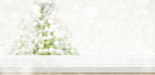 Fototapete - Empty white wooden table top with abstract muted blur christmas tree and snow fall background with bokeh light,Holiday backdrop,Mock up banner for display or montage of product