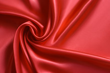 Close Up Of Ripplesin Shape Of Rose Flower In Red Silk Fabric. Satin Textile Background.