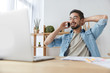 © wayhome.studio  - Positive carefree bearded male freelancer wears spectacles and denim shirt pleased to hear friend via smart phone, has break after work on laptop computer, shares his success and achievement.