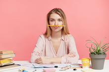 Funny Female Student Foolishes As Being Exhausted Of Studying, Pouts Lips And Keeps Pencil, Feels Bored, Wants To Have Entertainment Instead Of Learning Material, Isolated On Pink Background