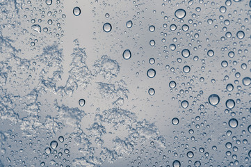 Multiple water drops with some frozen snow on a transparent glass window. Clean background.