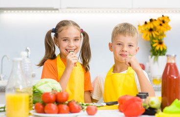 Happy children eat vegetables in the kitchen