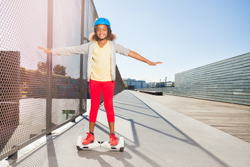 Wall Mural - African girl riding hoverboard on the side walk