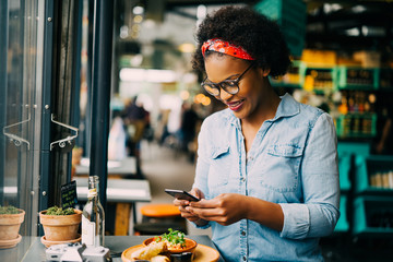 Smiling young woman photographing her food in a cafe