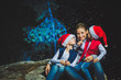 © Michael - Portrait of happy smiling young woman and cute kidboy with sparklers celebrating Christmas outdoors with decorated tree and lights. Christmas, New Year, winter and holidays seasons concept. Family.