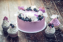 Purple Beautiful Cake Decorated With Berries, Blackberries And Blueberries On Top With Cupcakes On The Festive Table