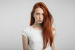 redhead teenage girl with healthy freckled skin looking at camera with serious emotion