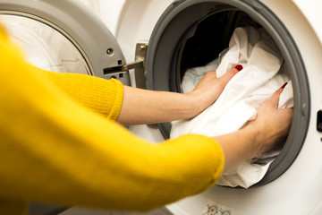 Woman hand loading dirty clothes in washing machine