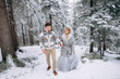 © Vadim Pastuh - Happy couple are walking holding hands in winter pine forest, woman in grey wedding dress and long veil, man in sweater