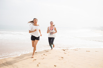 Wall Mural - two women is jogging the seashore on an overcast day