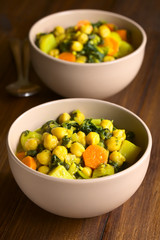 Wall Mural - Vegan chickpea curry or chana masala with spinach, potato and carrot, photographed with natural light (Selective Focus, Focus one third into the first curry)