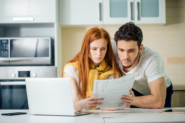 couple managing finances, reviewing their bank accounts using laptop computer to paying taxes online