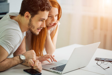 young Couple Using Laptop On Desk At Home and think